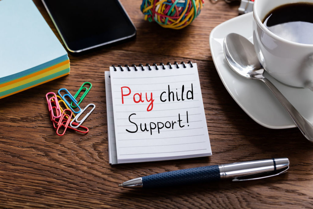 Child maintenance tribunal appeal guide: a note about paying child support on a table beside a pen and a cup of coffee