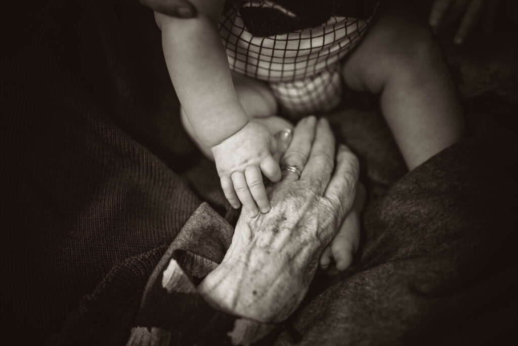 Child abandonment: an older carer's hand holding a baby's hand