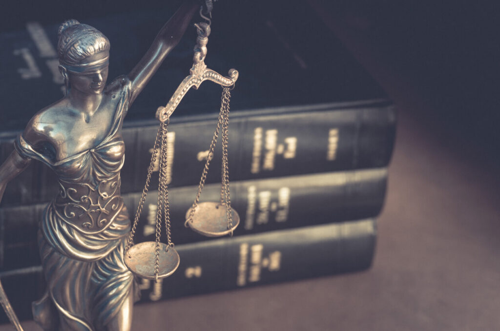 Lady Justice statue with scales in front of law books, illustrating this Warwickshire Justice Centre guide