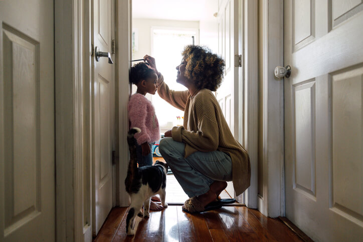 Changing a child's name: a parent at home marks a young girl's height on a doorframe