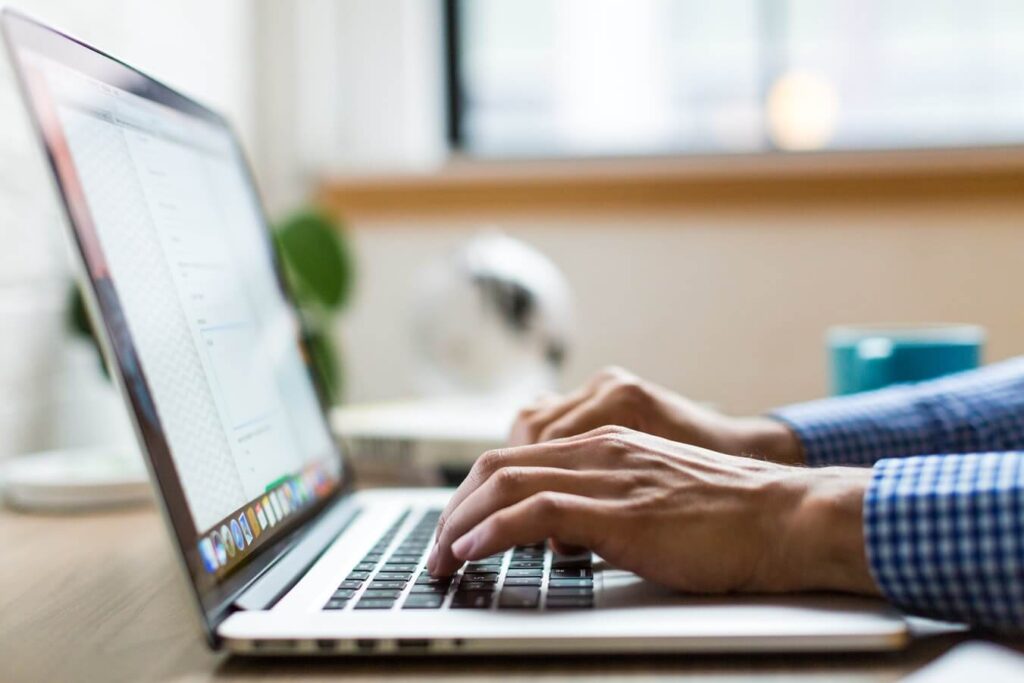 C1A form guide: hands typing on a laptop at a table by a window