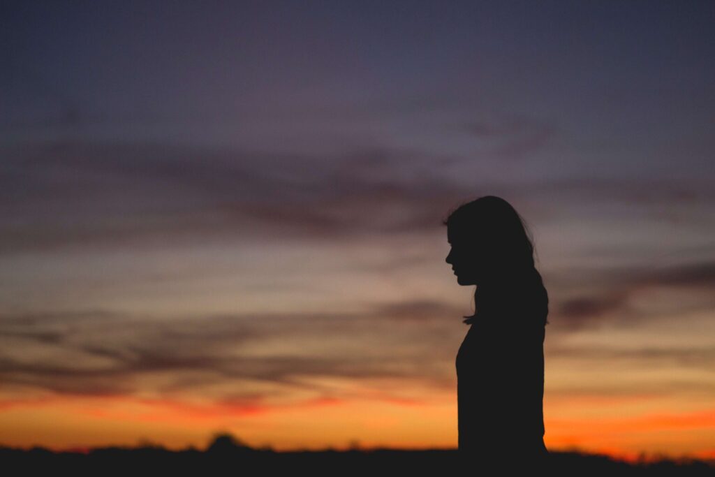 Emergency protection order guide: silhouette of a parent standing alone at dusk, head bowed
