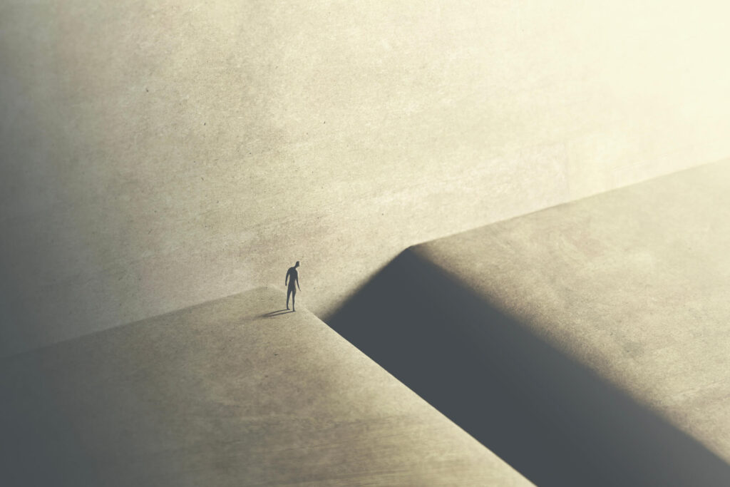 A lone figure stands at the edge of a deep gap between two stone blocks, head bowed, illustrating our EX160 form guide