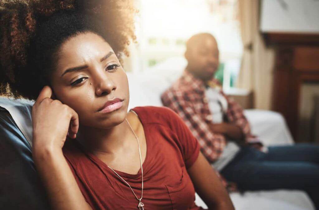 Narcissistic abuse can feel lonely: a woman sits quietly apart on a sofa while her partner looks away