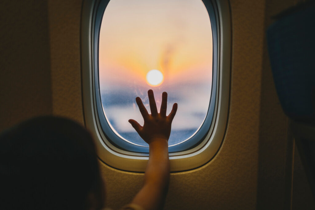 REMO and maintenance abroad: a child's hand pressed to an aeroplane window as the sun sets over the clouds